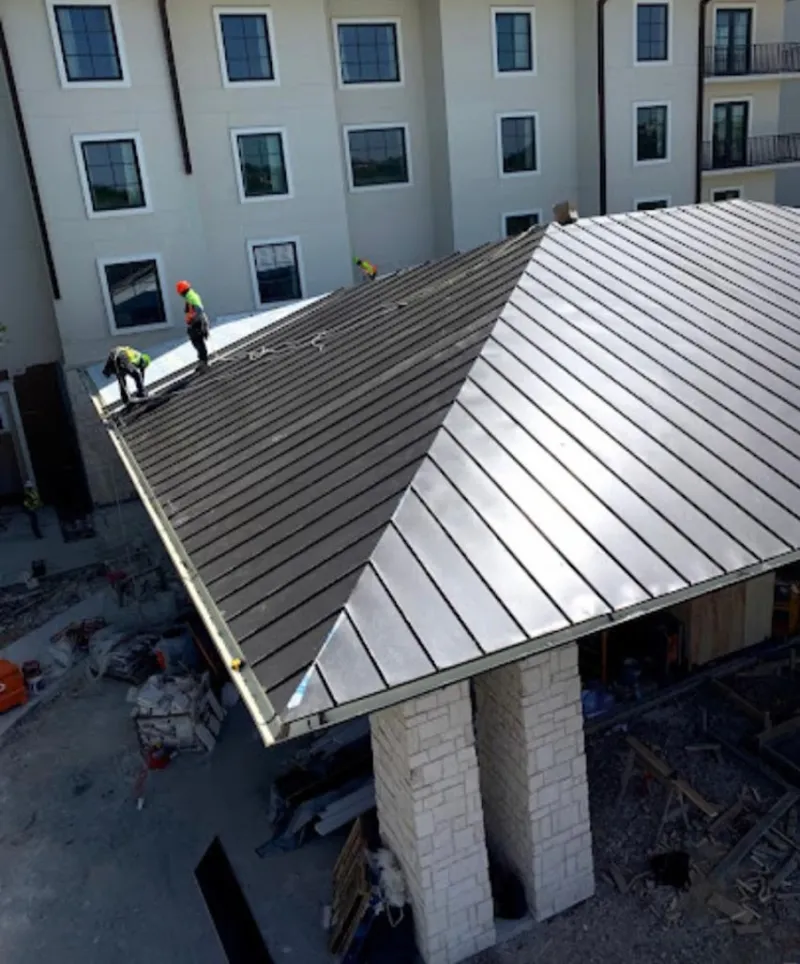 Crew installing standing seam metal roof panels on a commercial project in Home Gardens